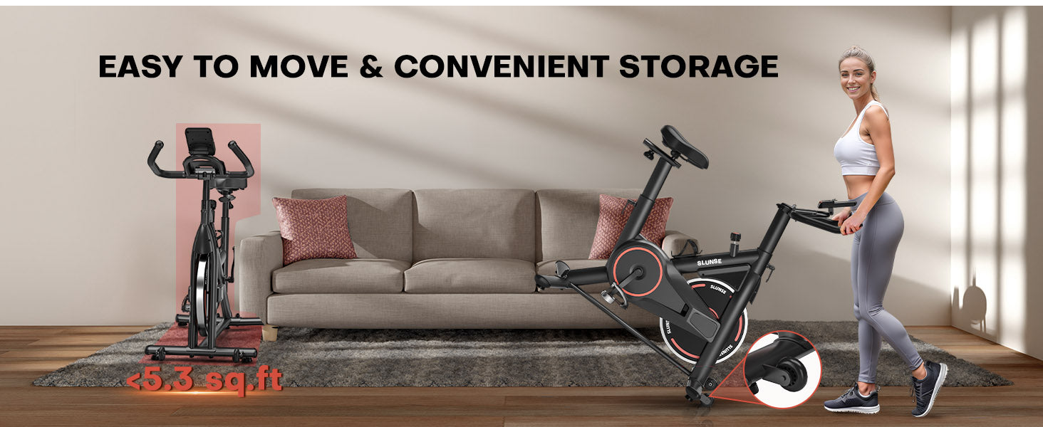 Ein Heimtrainer mit einer daneben stehenden Frau steht auf einem Holzboden in einem Wohnzimmer.